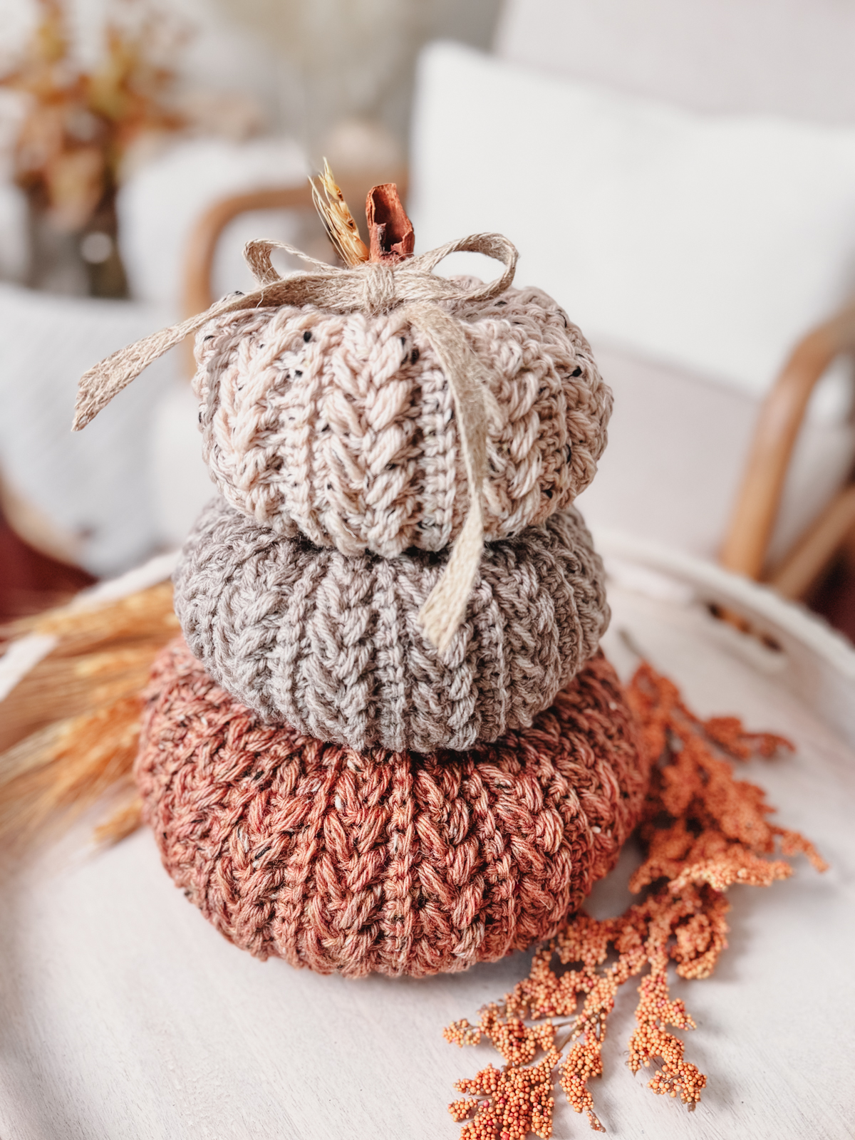 Stack of oatmeal and blush Wheat Stitch Crochet Pumpkins with a ribbon
