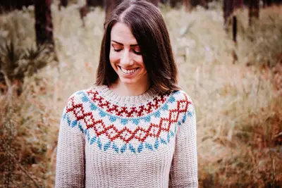 Woman wearing the Arizona Crochet Sweater Dress with a red and blue colorwork yoke outdoors