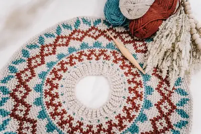 Flat lay of the Arizona Sweater Dress colorwork yoke in rust, cream and teal