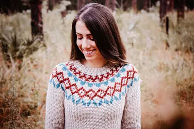 Arizona Crochet Sweater Dress shown on a model in a field, colorwork yoke in red and teal