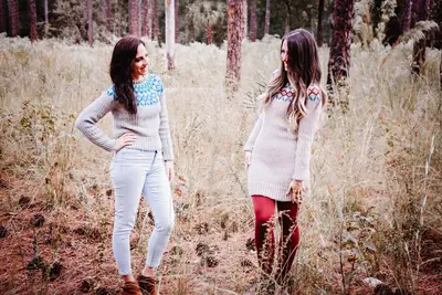 Two women wearing Arizona Crochet Sweater Dresses in a forest clearing