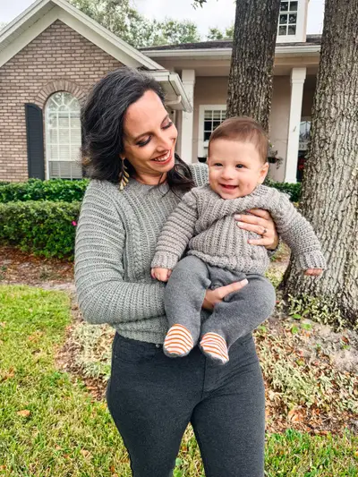 Mom holding a smiling baby, both wearing gray Autumn Wheat Flat Sweaters