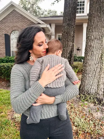 Mom and baby in matching gray Autumn Wheat Flat Sweaters outside a brick house