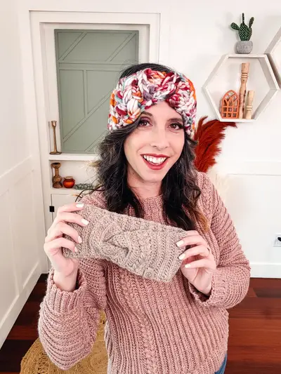 Woman holding an Autumn Wheat Ear Warmer while wearing a floral print one
