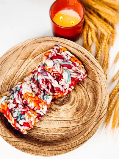 Floral multicolor Autumn Wheat Ear Warmer in a wooden bowl with a candle