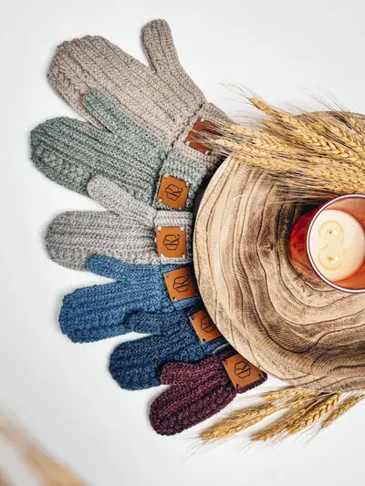 Autumn Wheat Flat Crochet Mittens in several colors around a wooden bowl and candle