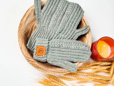 Pair of sage Autumn Wheat Flat Crochet Mittens in a woven basket