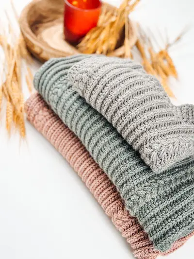 Autumn Wheat Flat Sweaters folded in gray, sage and blush with wheat and a candle