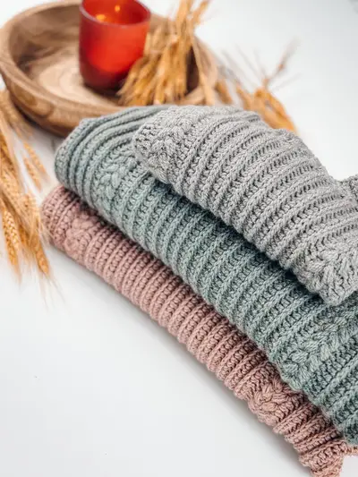 Stack of Autumn Wheat Flat Sweaters in gray, sage and blush