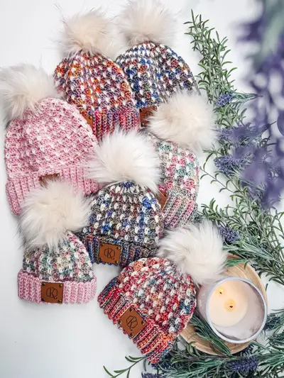 Block Stitch Beanies in speckled pink, plum and blue with cream faux fur pom poms