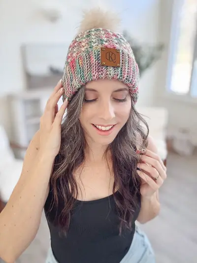 Woman wearing a speckled Block Stitch Beanie with a pom pom