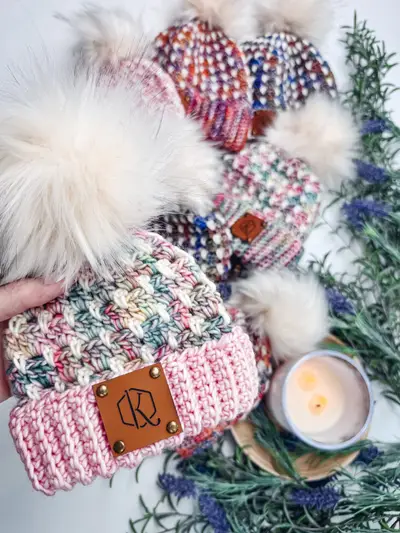 Close up of the block stitch texture on pink speckled beanies with pom poms