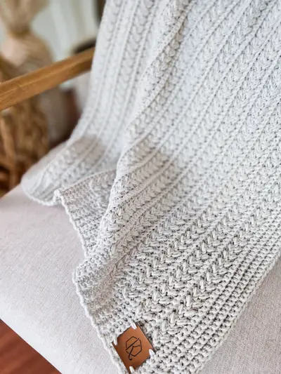 Light gray Braided Wheat Crochet Blanket with a braided cable texture and leather tag