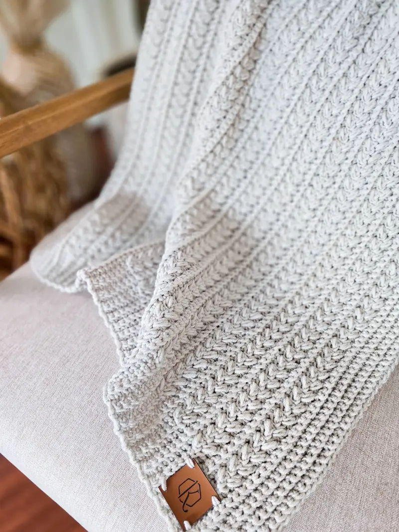 Light gray Braided Wheat Crochet Blanket with a braided cable texture and leather tag