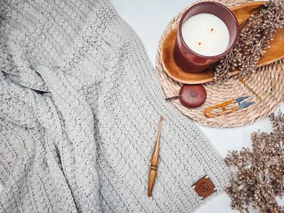 Folded light gray Braided Wheat Crochet Blanket with a candle and dried flowers
