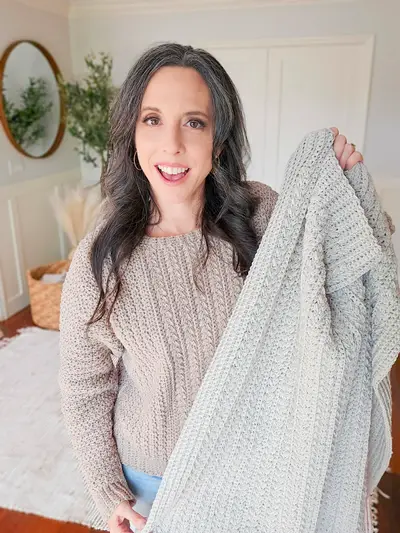 Woman holding up the light gray Braided Wheat Crochet Blanket