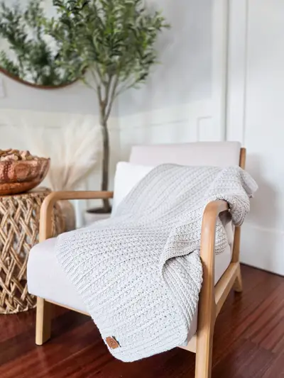 Light gray Braided Wheat Crochet Blanket draped over a wooden chair