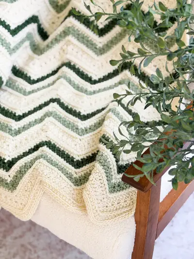 Close up of the cream and green chevron stripes of the Chevron Petal Loop Blanket
