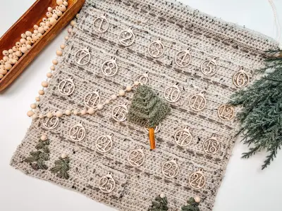 Christmas Wall Advent Calendar laid flat with a green crochet tree and wood bead garland