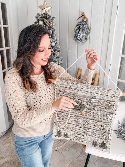 Woman hanging the oatmeal Christmas Wall Advent Calendar on a wooden dowel