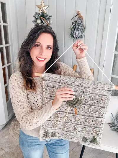 Smiling woman holding the Christmas Wall Advent Calendar by its hanging cord