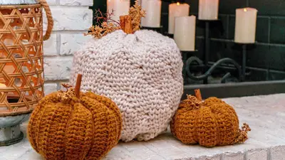 Cinderella's Crochet Pumpkin in cream beside two rust crochet pumpkins on a brick hearth