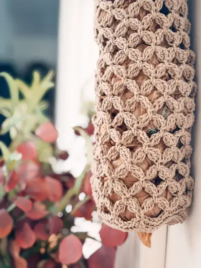 Tan Circle Leaf Plastic Bag Holder hanging, a long lacy mesh tube