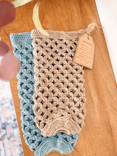 Circle Leaf Plastic Bag Holders in tan and light blue laid flat on wood with a gift tag