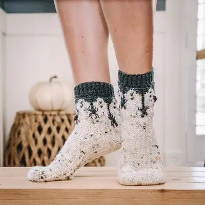 Creepy Crawly Spider Crochet Socks in cream with charcoal cuffs on a wooden ledge