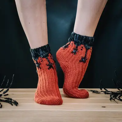 Feet in orange Creepy Crawly Spider Crochet Socks with charcoal cuffs