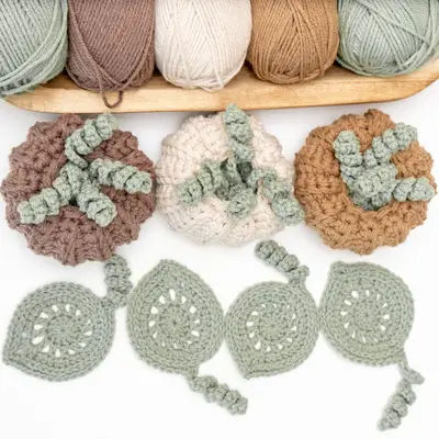 Crochet Pumpkins with Leaf Coasters in brown, cream and gold with sage leaves and skeins of yarn