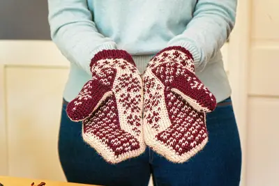 Person holding Deer Fair Isle Crochet Mittens in burgundy and cream