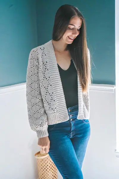 Woman wearing the light gray Diamond Crochet Cardigan open over a black top
