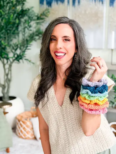 Woman wearing a stack of rainbow Double Bloom Scrunchies on her wrist