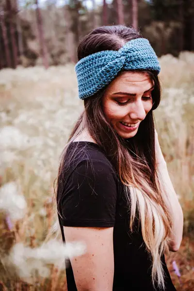 Smiling woman wearing a teal Easy Crochet Ear Warmer with a twisted front