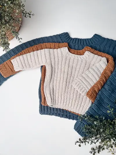 Easy Cuff to Cuff Child Crochet Sweater in cream with a rust and navy sleeve, laid flat