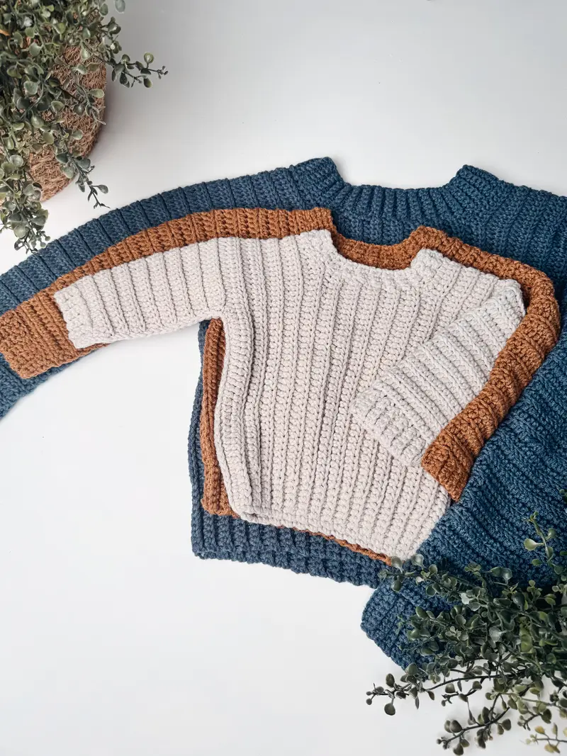 Easy Cuff to Cuff Child Crochet Sweater in cream with a rust and navy sleeve, laid flat