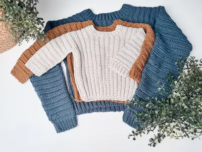 Two Easy Cuff to Cuff Child Crochet Sweaters in cream with rust and blue edges