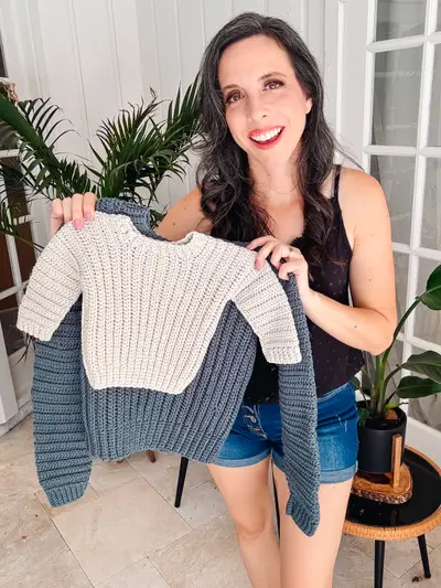 Woman holding up a cream and blue Easy Cuff to Cuff Child Crochet Sweater