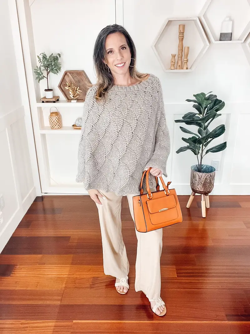 Woman wearing the gray Enchanted Crochet Poncho with a cognac handbag
