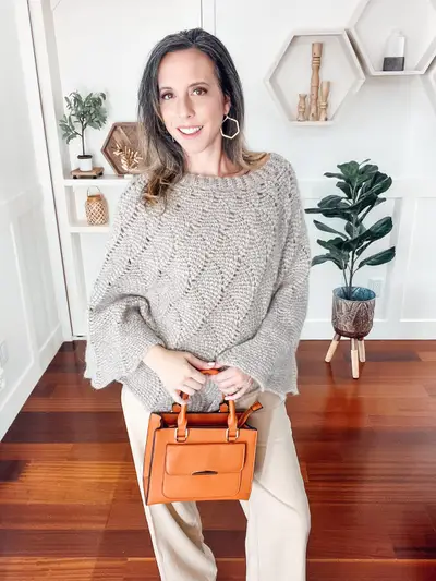 Gray Enchanted Crochet Poncho worn with cream pants and a brown bag