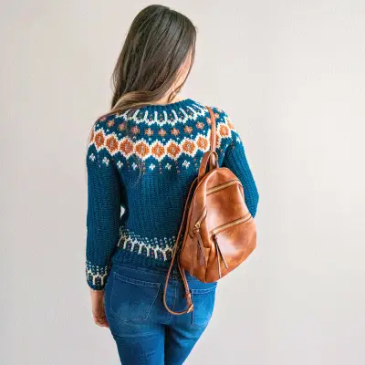 Back view of the teal Fawning Over You Crochet Sweater with a leather backpack
