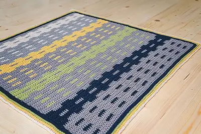 Garden Fences Crochet Blanket laid flat on a wood floor