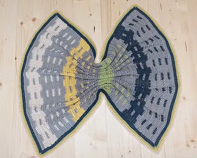Garden Fences Crochet Blanket folded into a fan shape on a wood floor