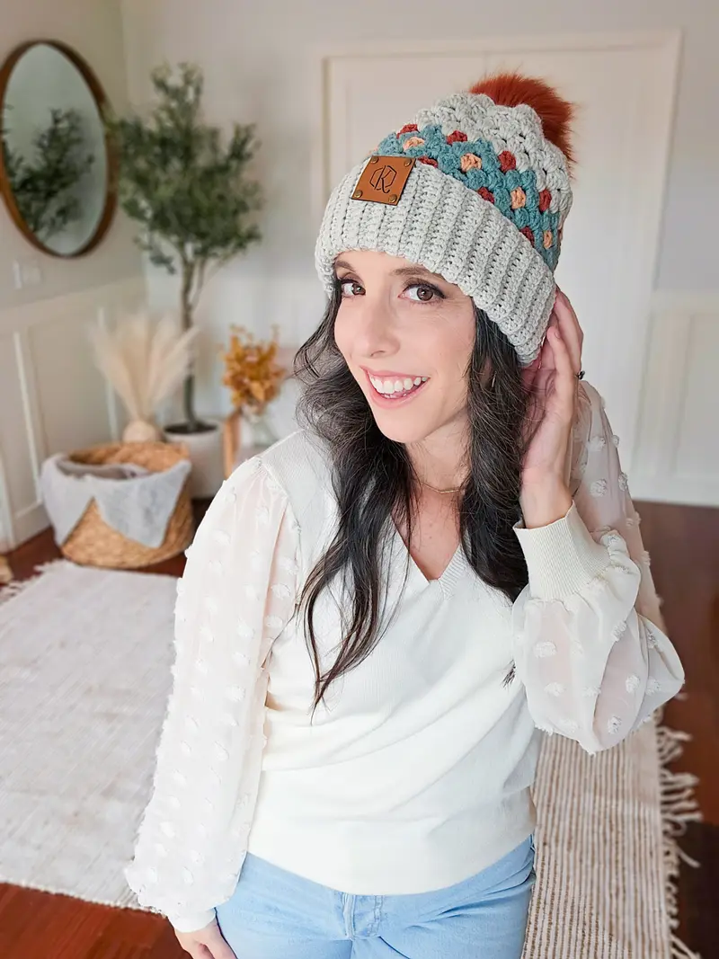 Woman wearing a gray Gemstone Hues Crochet Beanie with a colorful band and pom pom