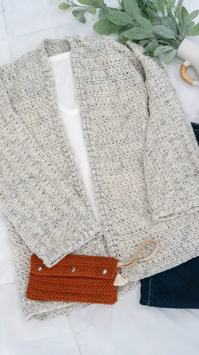 Get Comfy Crochet Cardigan in heathered oatmeal laid flat with a rust clutch
