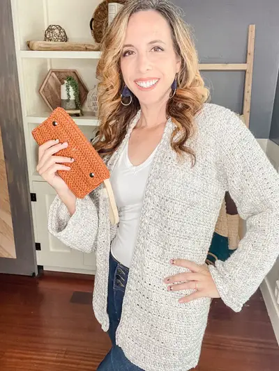 Woman wearing the oatmeal Get Comfy Crochet Cardigan holding a rust clutch