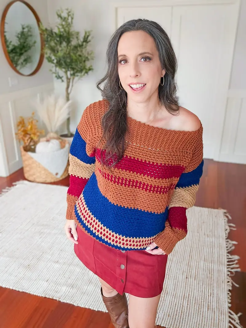 Woman wearing the Gingersnap Pullover in rust, navy, red and gray stripes off the shoulder