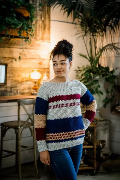 Model in the gray, navy and red Gingersnap Pullover in a cafe setting