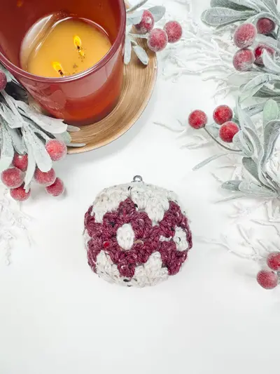 Burgundy and cream Granny All the Way Ornament beside a candle and berries